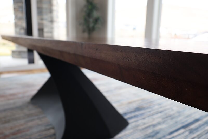 Close-up of the Gathering Place table where the black steel base meets the walnut top